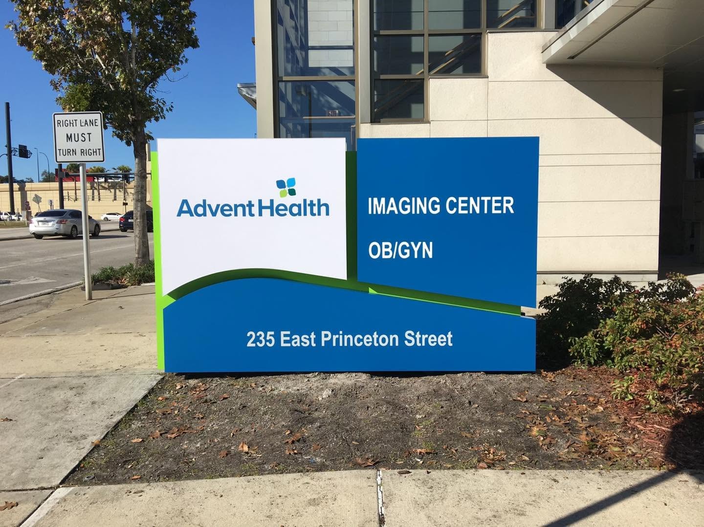 AdventHealth Imaging Center and OB/GYN monument sign with a curved blue and green base and street address