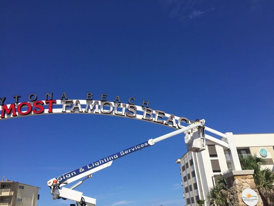 Technician in the bucket of an SOS Sign & Lighting boom truck servicing the World's Most Famous Beach arch in Daytona Beach, FL