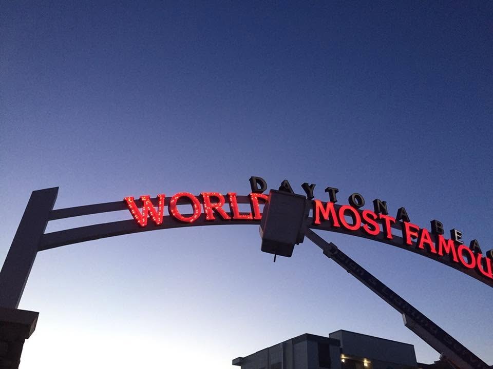 Red lit letters on the World's Most Famous Beach arch at dusk after service, Daytona Beach, FL