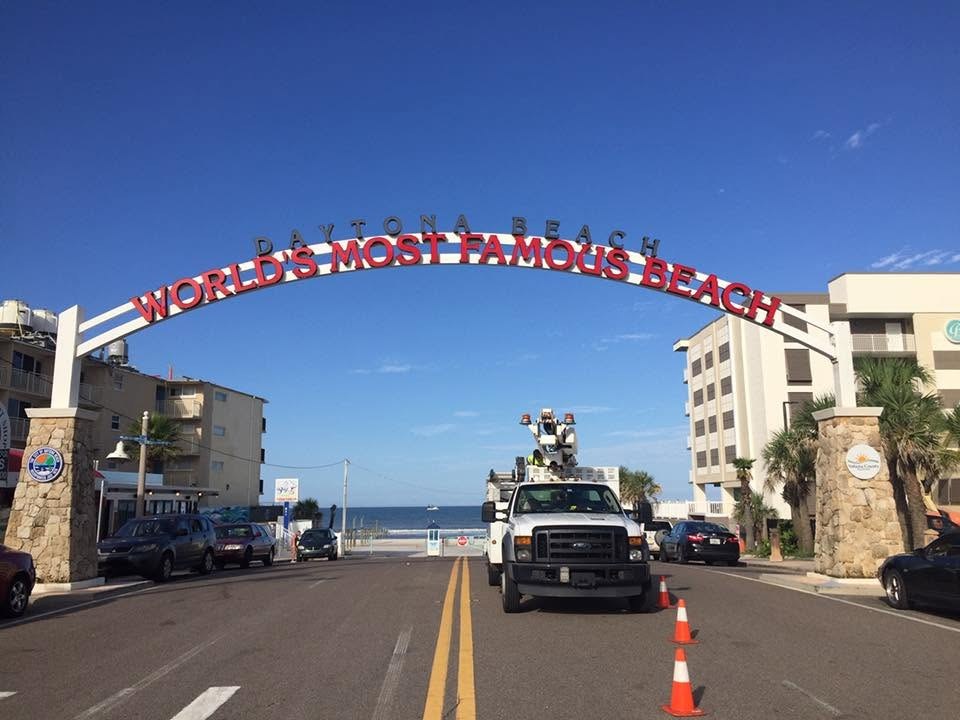 SOS Sign & Lighting bucket truck servicing the lettering on the World's Most Famous Beach arch over the street in Daytona Beach, FL
